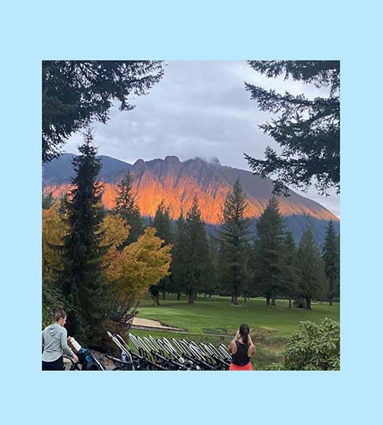 The bright orange glow of the mountains loom over the trees surrounding the ecourse.